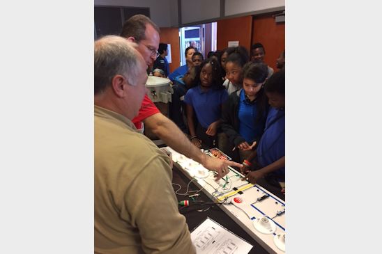 Entergy employees Randall Roberts and Mark Bacques show students an interactive electrical circuit experiment that was among the exhibits Entergy displayed during the National Engineers Week celebration at the University of New Orleans. 